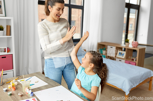 Image of mother with daughter drawing and making high five