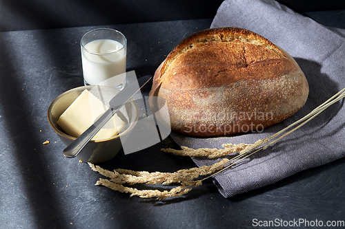 Image of close up of bread, butter, knife and glass of milk