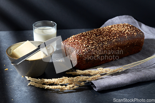 Image of close up of bread, butter, knife and glass of milk