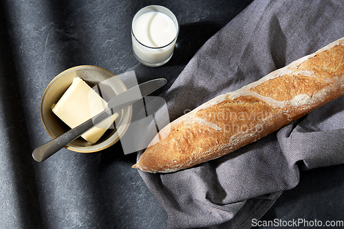 Image of close up of bread, butter, knife and glass of milk