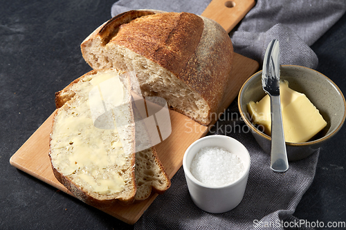 Image of close up of bread, butter, knife and salt on towel