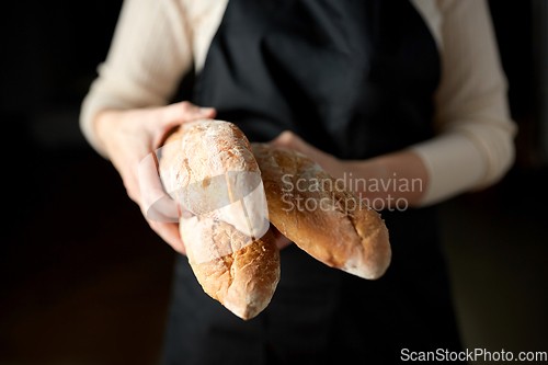 Image of close up of female baker holding baguette bread