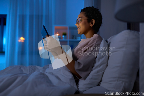 Image of woman with tablet pc in bed at home at night