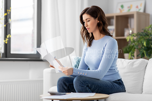 Image of woman with papers and calculator at home