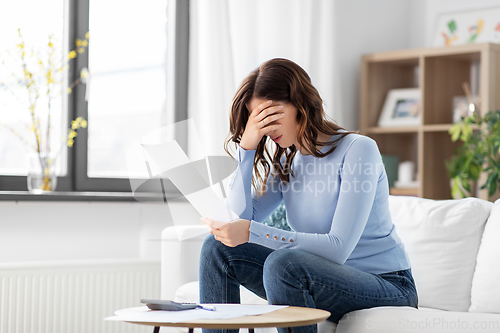 Image of stressed woman with papers and calculator at home