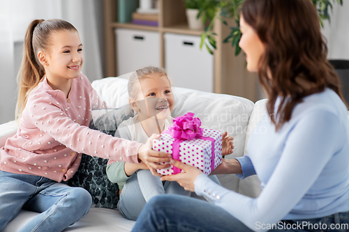 Image of daughters giving present to happy mother