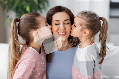 Image of happy mother and two daughters kissing her at home