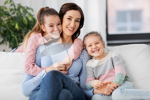 Image of happy smiling mother with two daughters at home