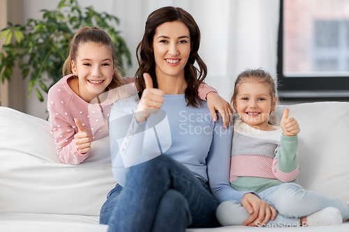 Image of mother and daughters showing thumbs up at home