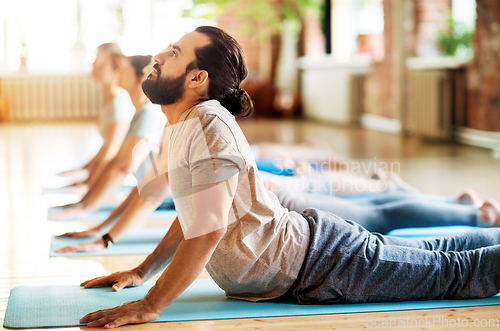 Image of group of people doing yoga cobra pose at studio