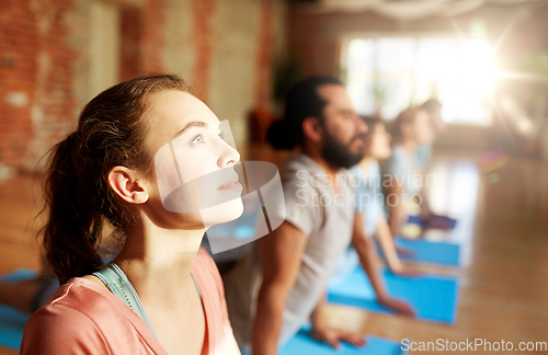 Image of group of people doing yoga cobra pose at studio