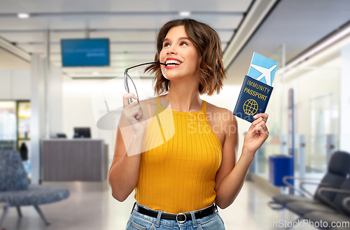 Image of happy woman with air ticket and immunity passport