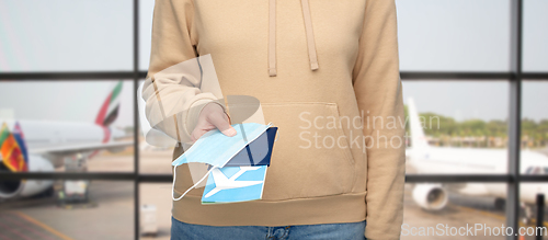 Image of woman with mask, passport and ticket at airport