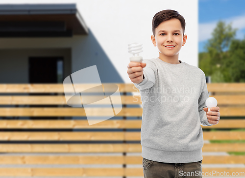 Image of boy comparing different light bulbs over house