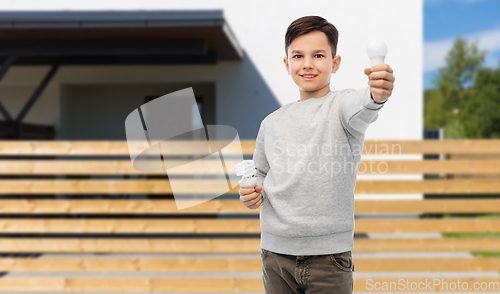 Image of boy comparing different light bulbs over house