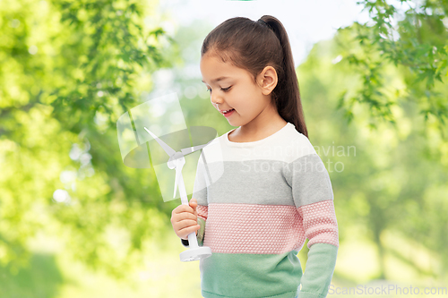 Image of girl with toy wind turbine over natural background