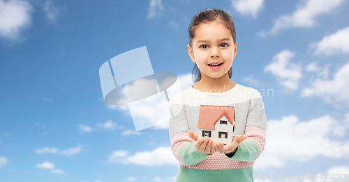 Image of happy girl holding house model over sky and clouds