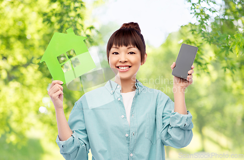 Image of smiling asian woman holding green house