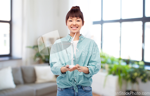 Image of smiling young asian woman with toy wind turbine