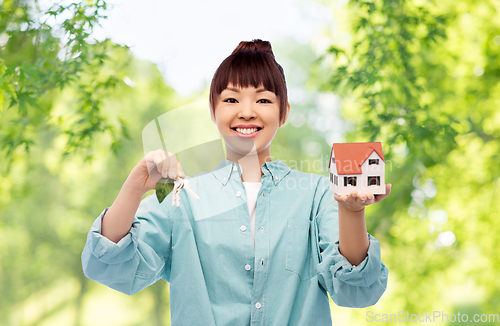 Image of smiling asian woman holding house model and keys