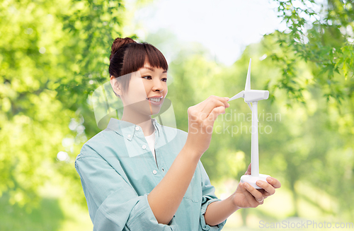 Image of smiling young asian woman with toy wind turbine