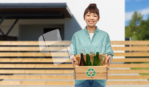 Image of smiling young asian woman sorting glass waste