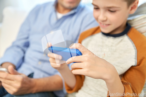 Image of father and son with smartphones at home