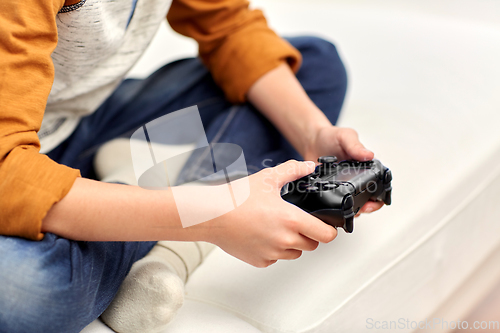 Image of boy with gamepad playing video game at home