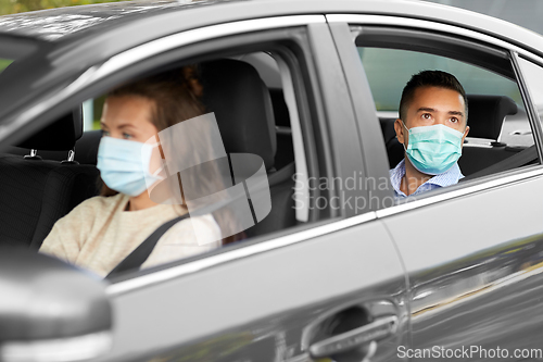 Image of female driver in mask driving car with passenger