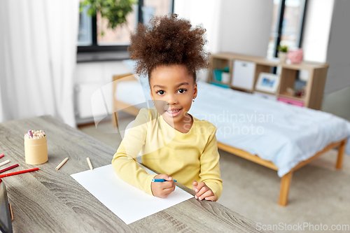 Image of little girl drawing with coloring pencils at home
