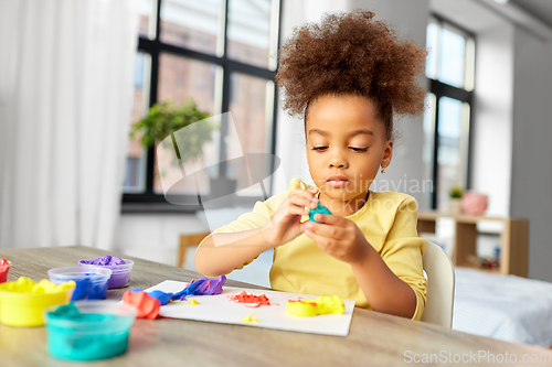 Image of little girl with modeling clay playing at home