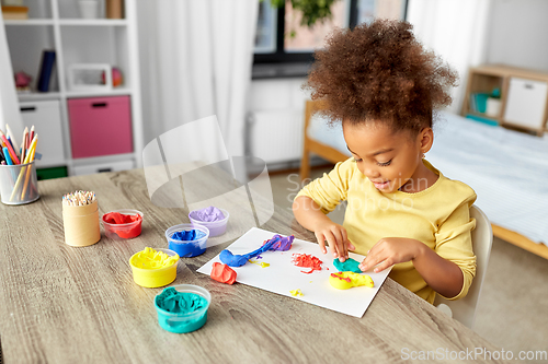 Image of little girl with modeling clay playing at home