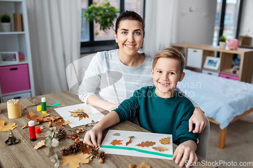 Image of mother and son making pictures of autumn leaves