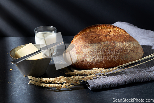 Image of close up of bread, butter, knife and glass of milk