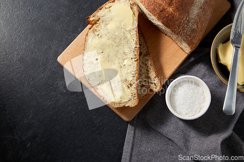 Image of close up of bread, butter, knife and salt on towel