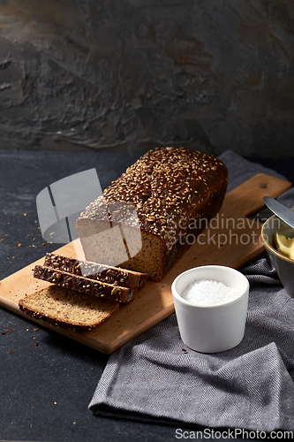 Image of close up of bread, butter, knife and salt on towel