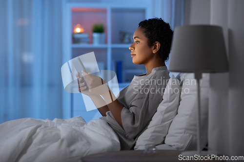 Image of woman with tablet pc in bed at home at night