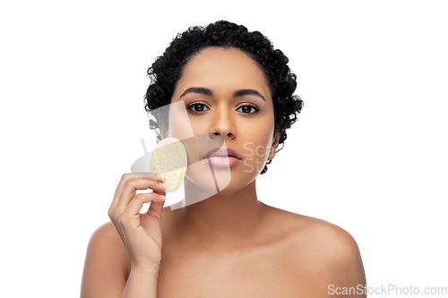 Image of young woman cleaning face with exfoliating sponge