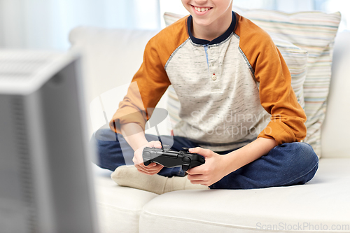 Image of happy boy with gamepad playing video game at home