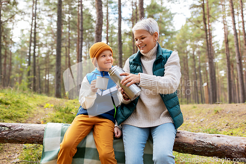 Image of grandmother with grandson drinking tea in forest