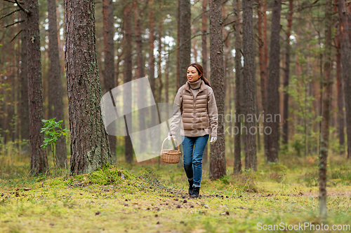 Image of young woman picking mushrooms in autumn forest