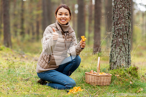 Image of woman with mushrooms showing thumbs up in forest