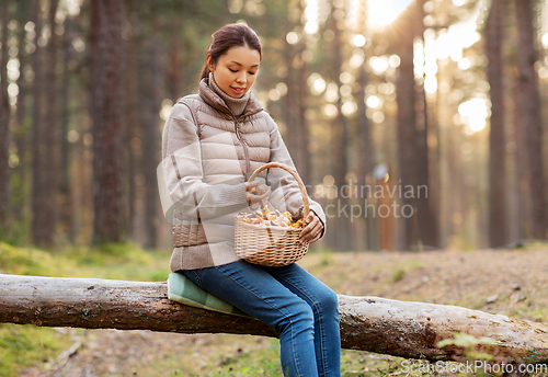 Image of woman with mushrooms in basket in autumn forest