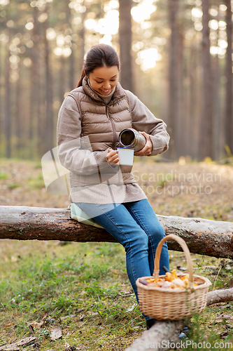 Image of asian woman with thermos drinking tea in forest