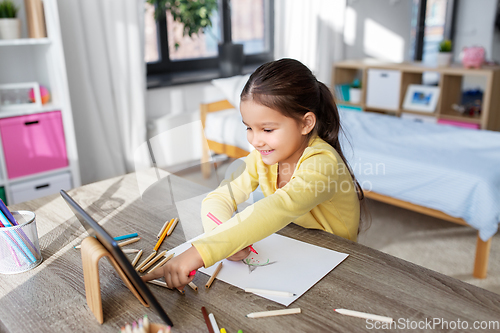 Image of little girl drawing with coloring pencils at home