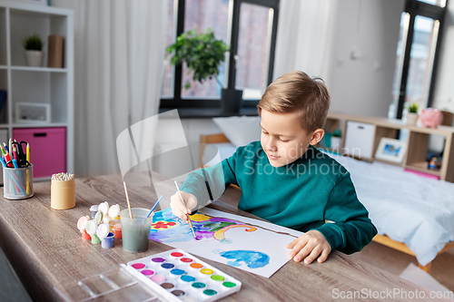 Image of boy with colors and brush drawing picture at home