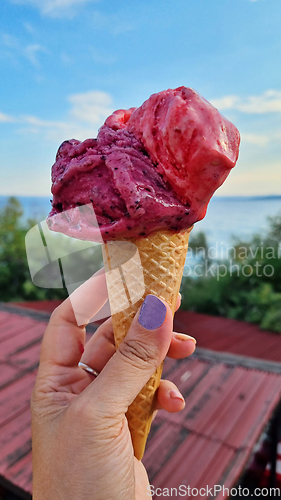 Image of Gelato ice cream cone held up to the hot summer city