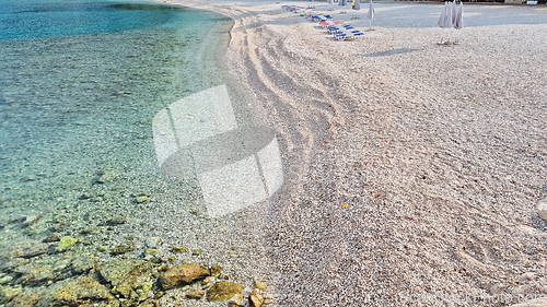 Image of Beautiful shore of the Adriatic Sea. Bay view with beach and deck chairs. Sunrise