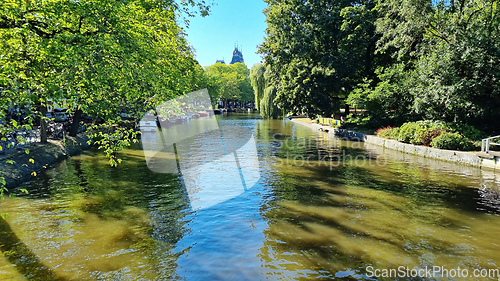 Image of Channel in Amsterdam Netherlands. Big trees near river Amstel landmark. Old European city summer landscape