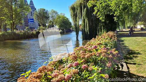 Image of Channel in Amsterdam Netherlands. Big trees near river Amstel landmark. Old European city summer landscape